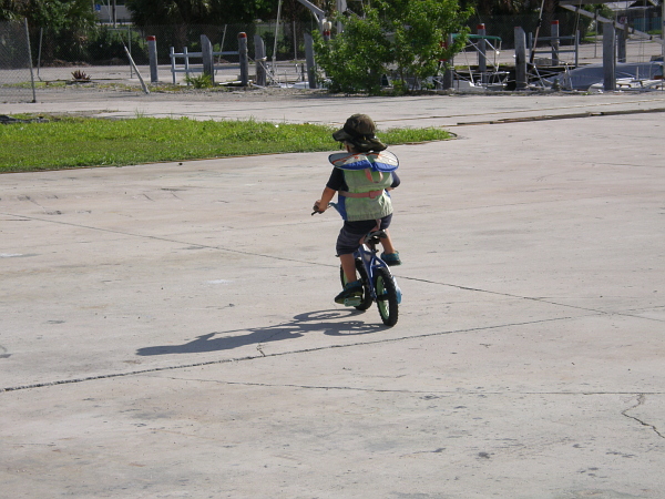 Boy riding bicycle in a life vest.