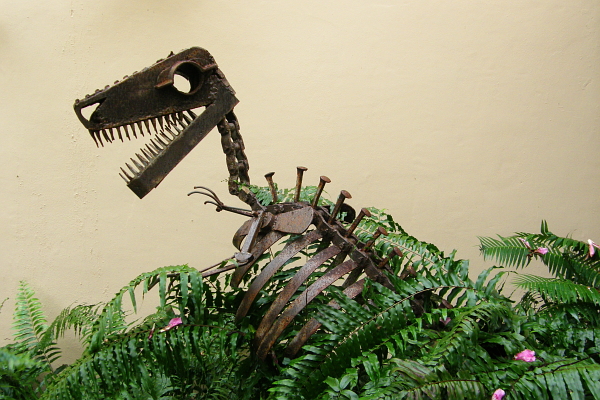 Dinosaur sculpture overgrown with ferns