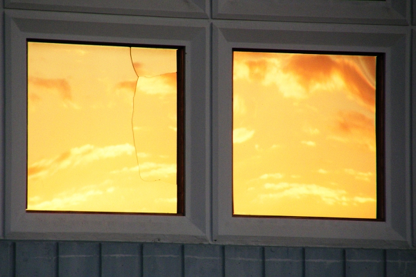Reflection of the sunset in cracked and warped windows.