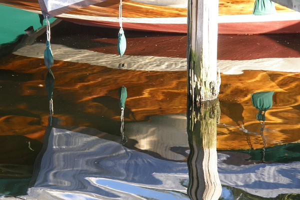 Reflection of a wooden boat in the water.