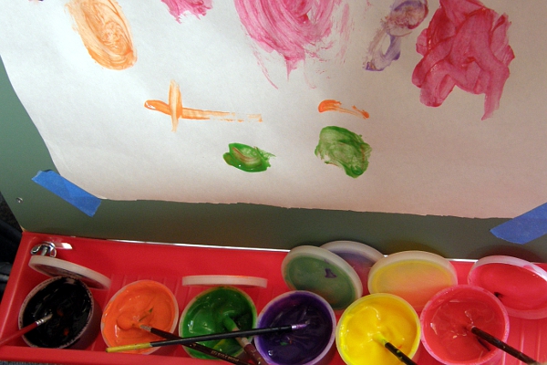 Tubs of finger paints with paintbrushes in them