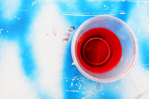 Red energy drink against a blue spray painted background.