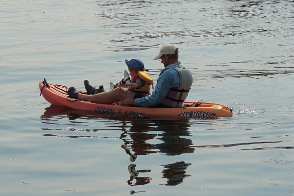 Father and child in kayak with child paddling.
