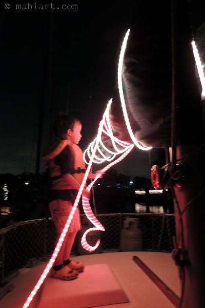 Boy decorating sailboat boom with Christmas light string