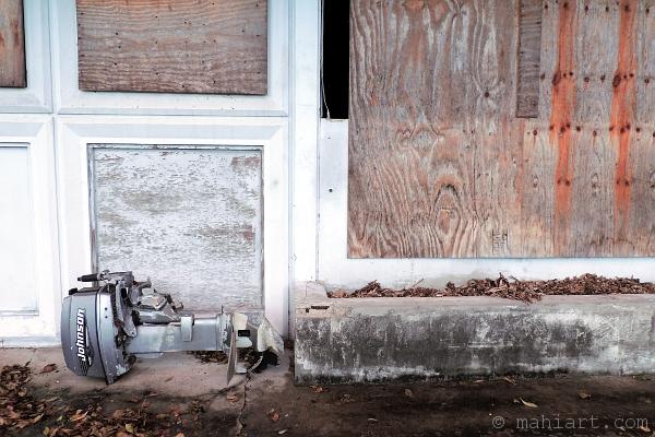 Outboard motor stored by old boarded up building