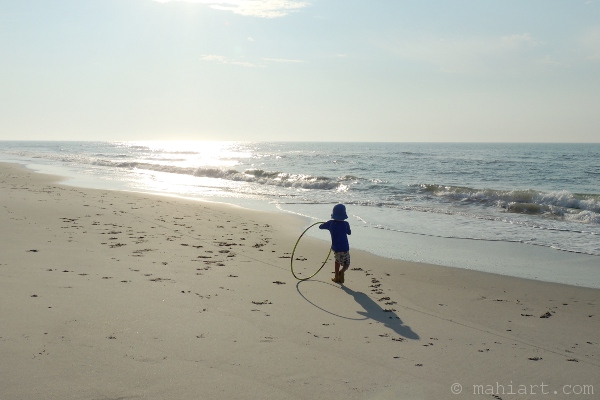Child playing with hoola hoop on beach