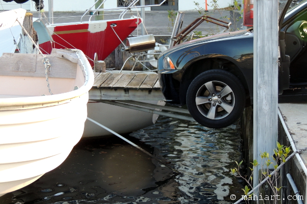 Car hanging over the edge of the water at a marina.