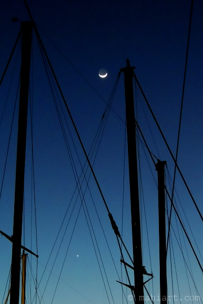Moon and venus seen shinging through sailboat masts and rigging.