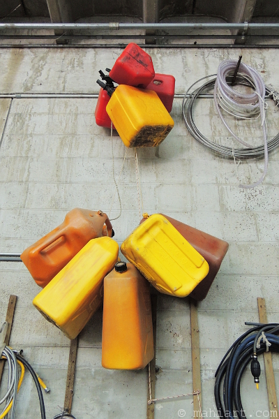 Empty fuel jugs bundled together and suspended on a wall